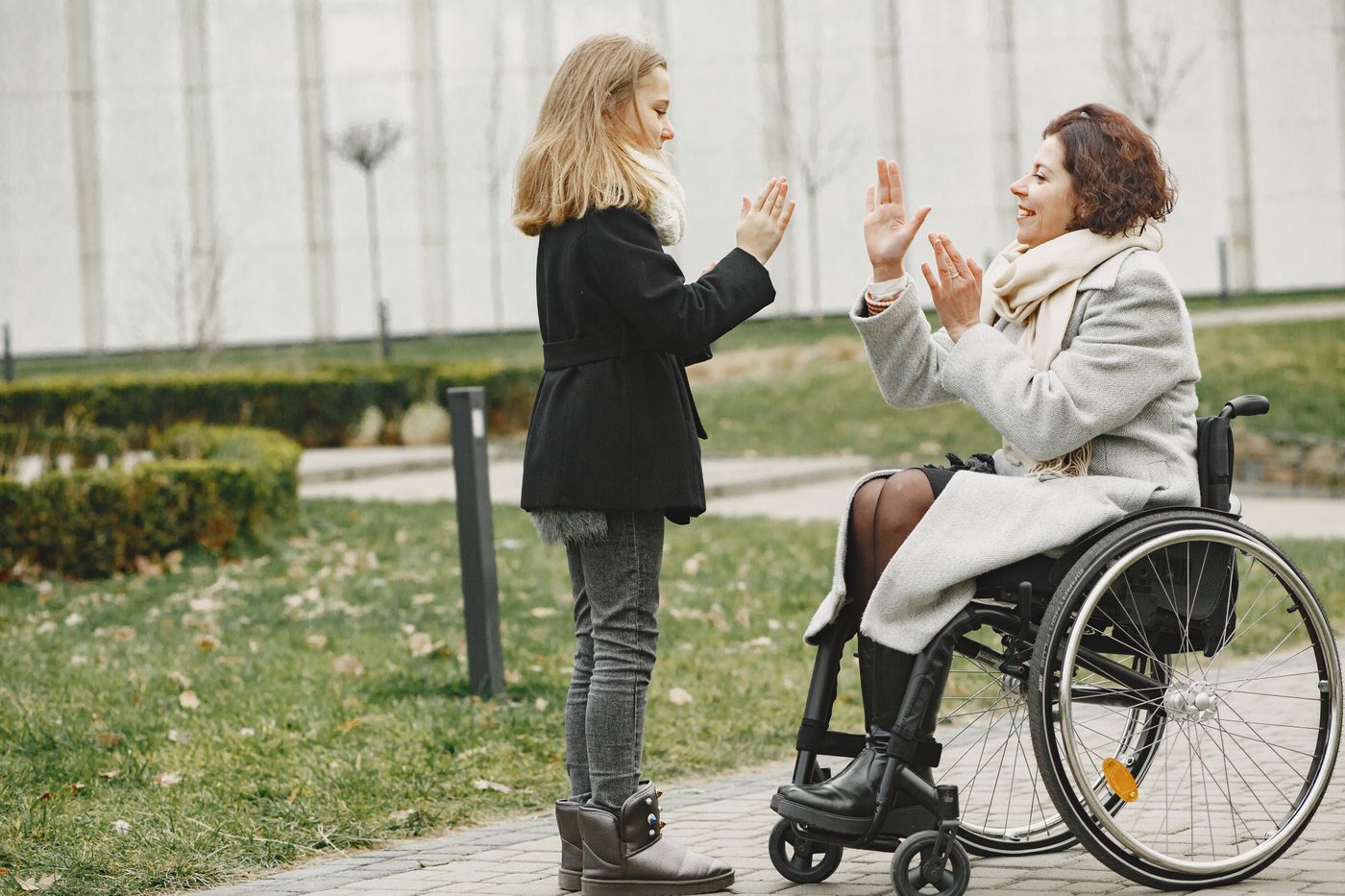A woman in a wheelchair sharing a high-five at the park
