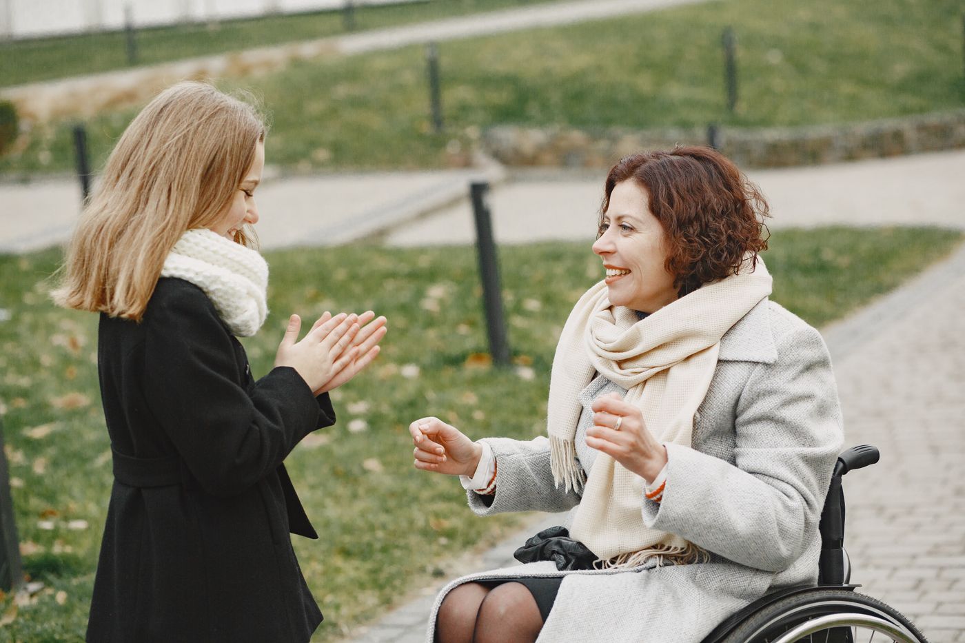 A woman in a wheelchair sharing a joyful moment with a young girl at the park