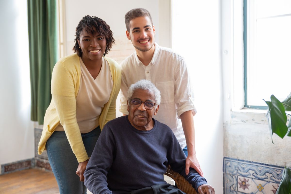 Support workers at home with a participant seated in his wheelchair