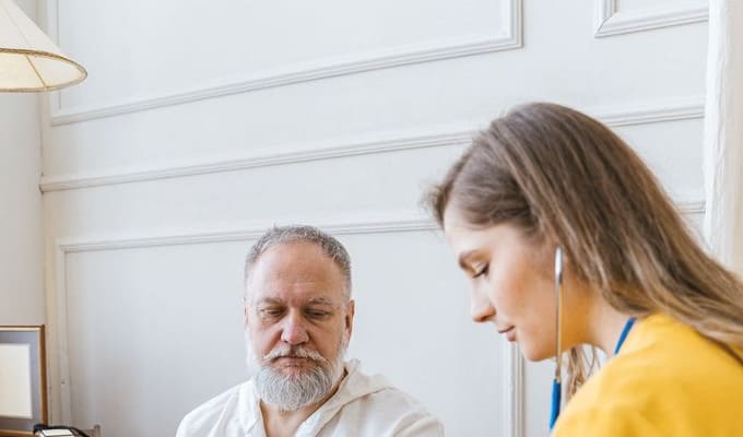 A nurse providing clinical care to an older man at home