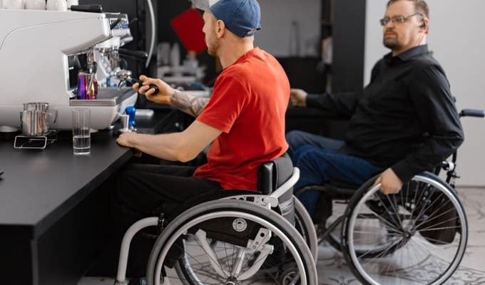 Two men in wheelchairs at work in an accessible café